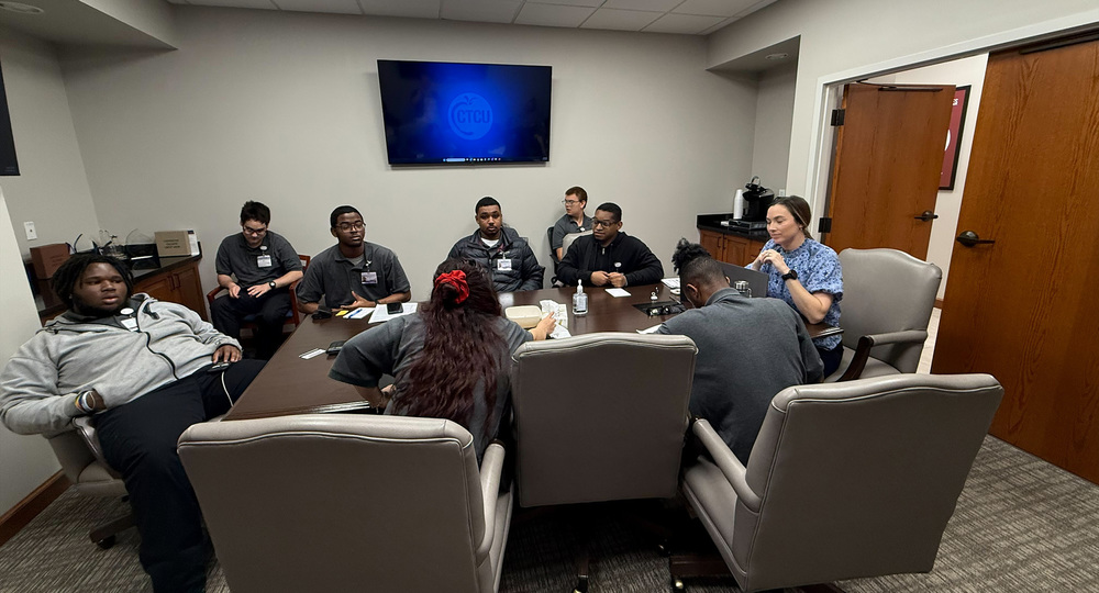 teen students sitting around table in office
