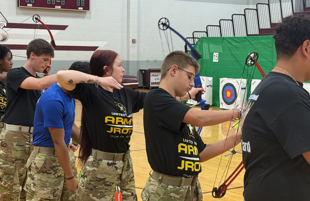 teen boys and girls with bows and arrows in archery class