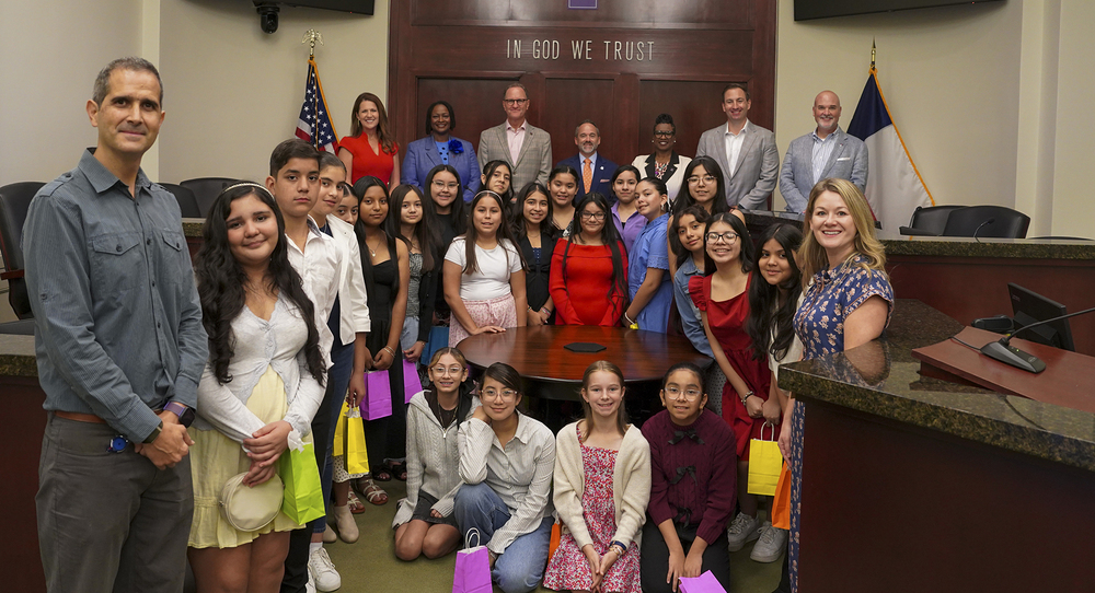 group of middle school students standing in courtroom with men and women behind them