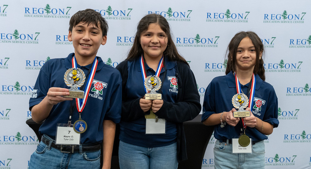 boy and two girls holding medals and trophies