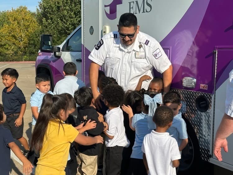 Bonner students gather around an emergency medical services worker beside an ambulance during their community helpers week.