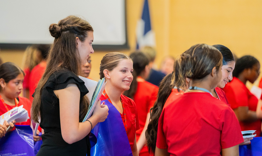 teen girls in a group smiling as they listen to someone explain an xray