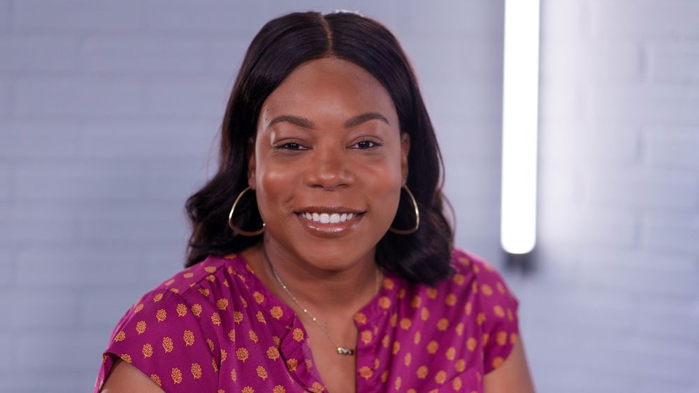 African American woman wearing hoop earrings and a pink with orange dots blouse