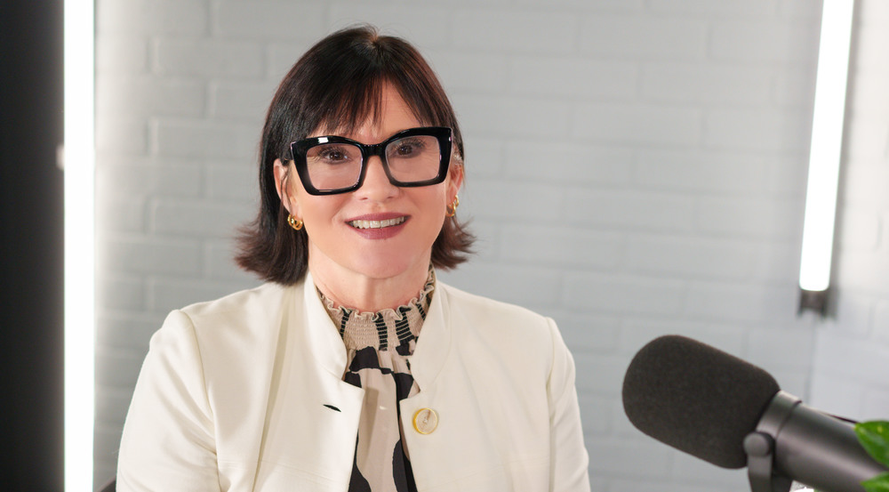 woman with short dark hair and thick black glasses wearing white jacket