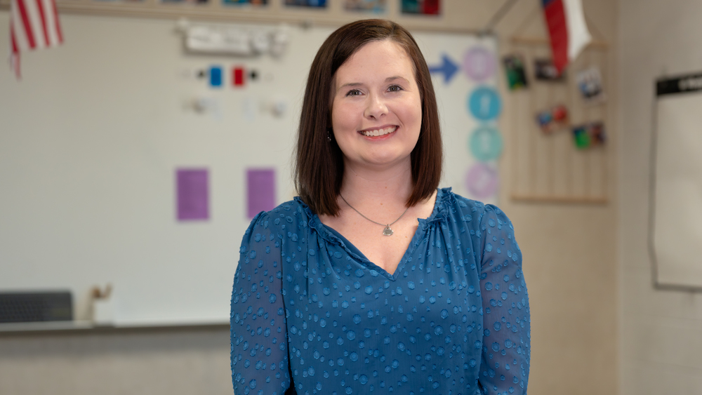 woman with shoulder length brown hair standing in her classroom