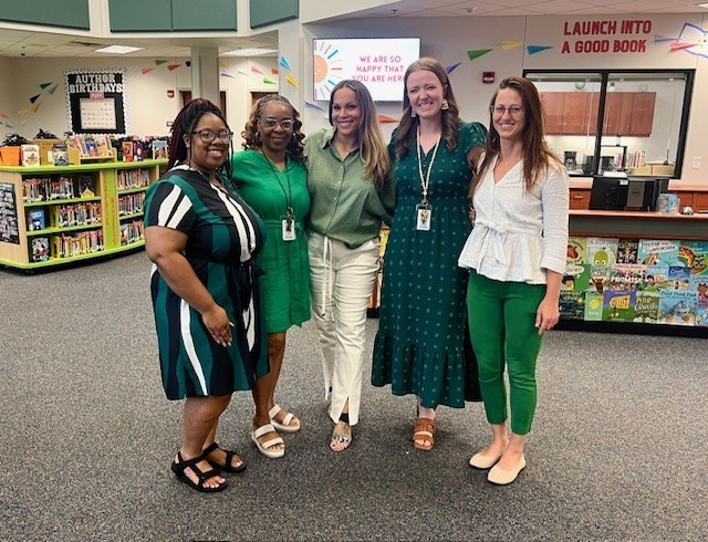 Five people wearing green standing next to eachother smiling