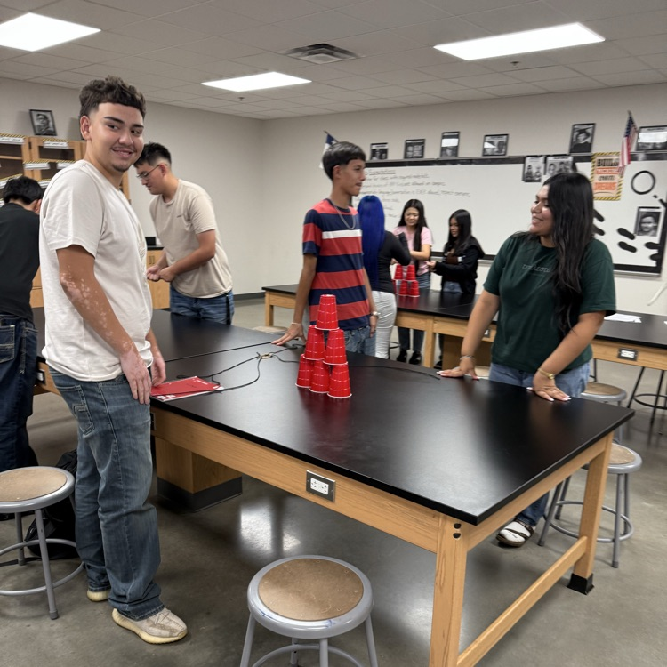 students at lab table with tower of cups