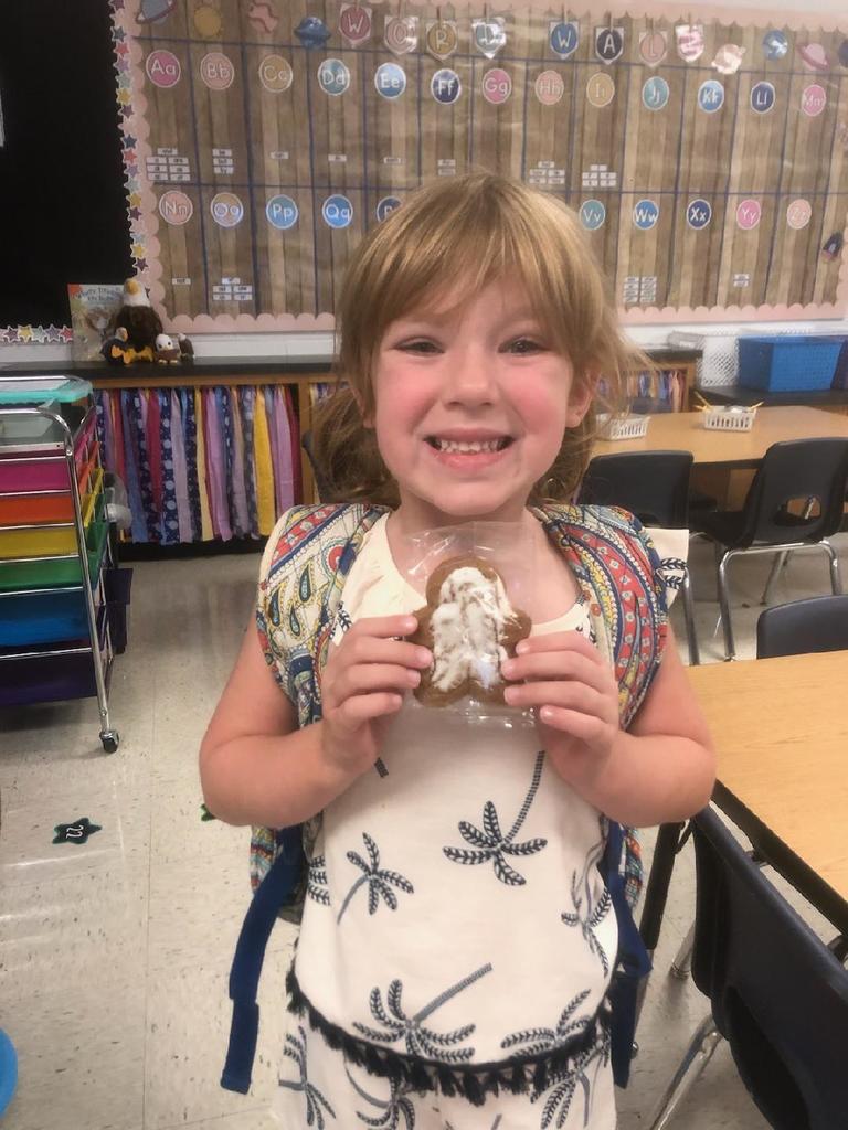 Students holding a gingerbread cookies.