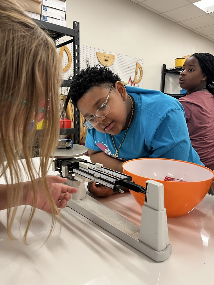 students measuring mass using a triple beam balance