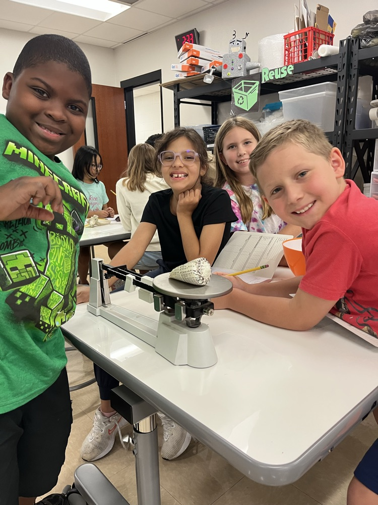 students measuring mass using a triple beam balance