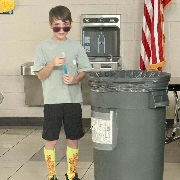 Student with popsicle and sunglasses standing next to trashcan