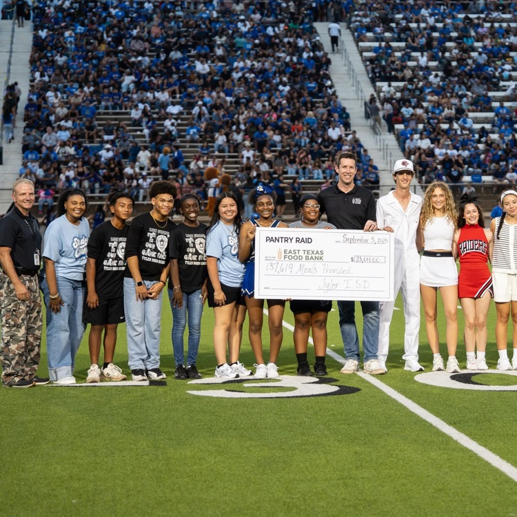students on field holding check