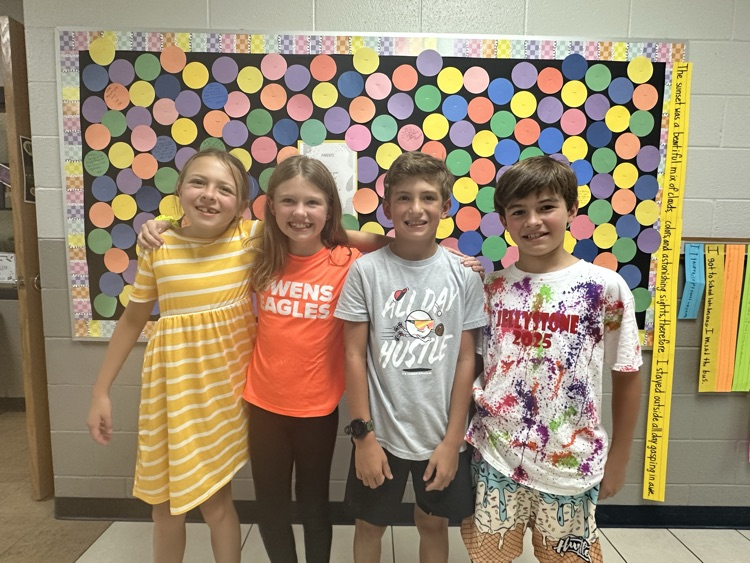 4 students- 2 female and 2 male- standing next to each other in the hall.