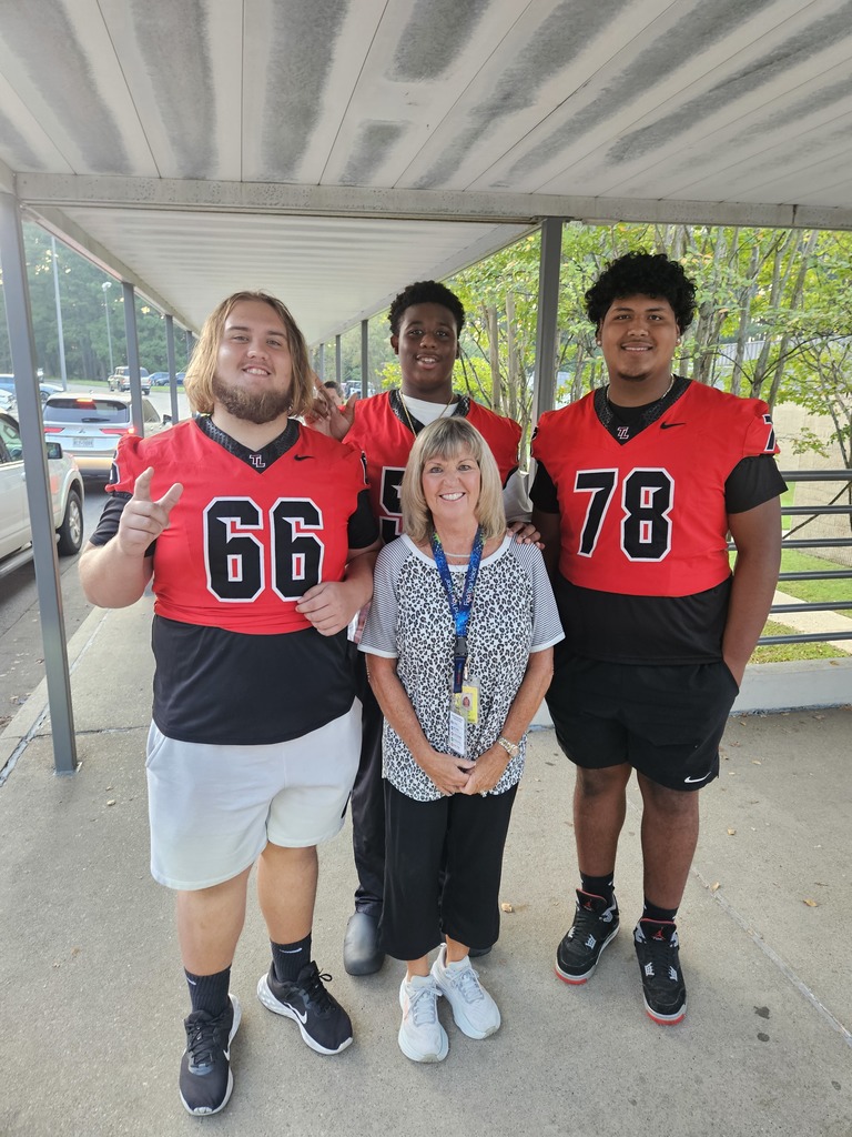 Football players posing with teacher.