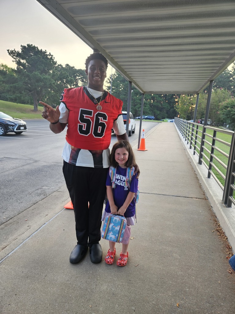 Football player helping students out of cars.