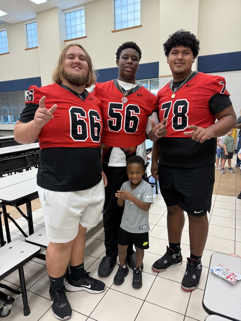 Football players posing with student .