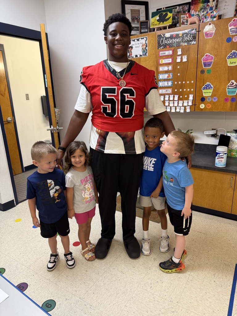 Football players posing with students.