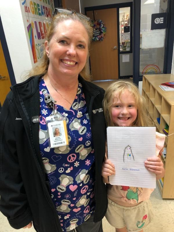 Student holding a picture of the nurse that she drew.