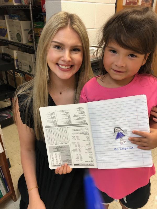 Student holding a picture of the assistant principal that she drew.