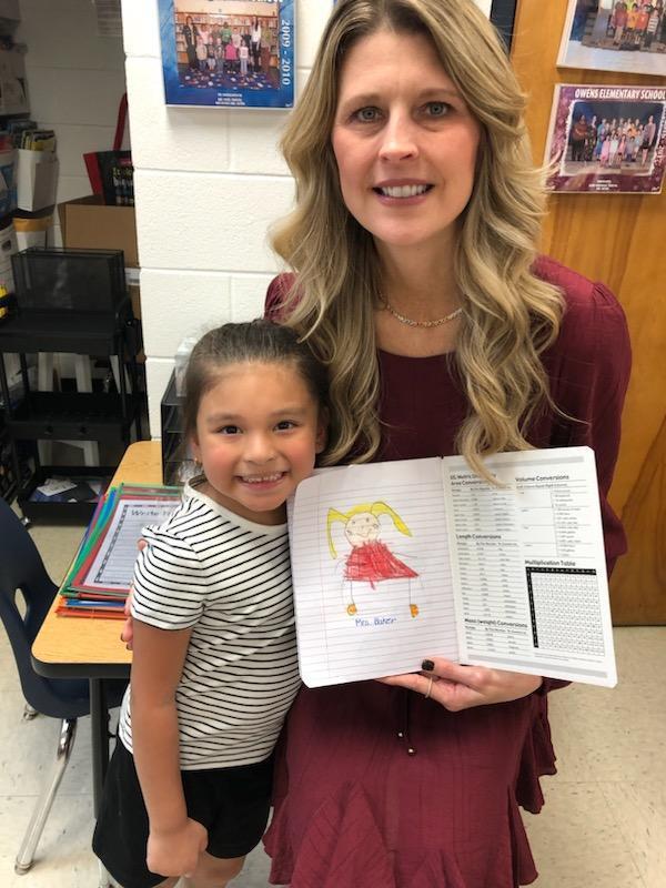 Student holding a picture of the principal that she drew.