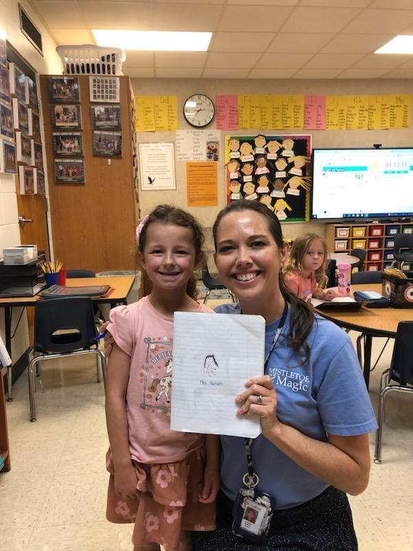 Student holding a picture of the teacher that she drew.