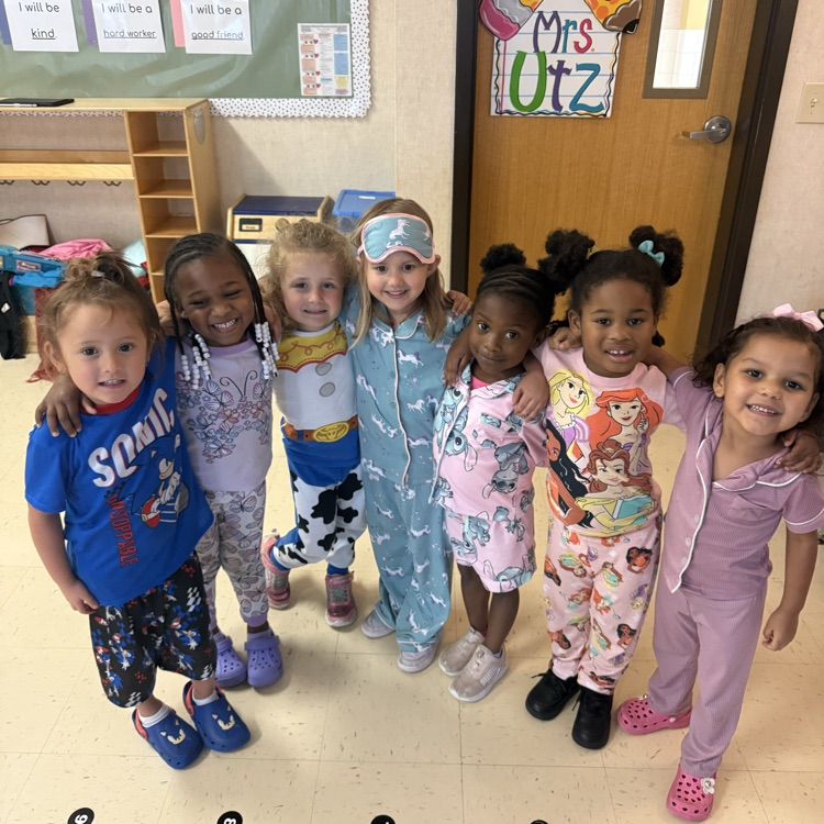 Students dressed up in pajamas with their arms around each other’s shoulders