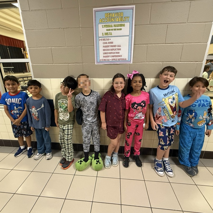 Students dressed up in pajamas, lined up along the wall in the hallway