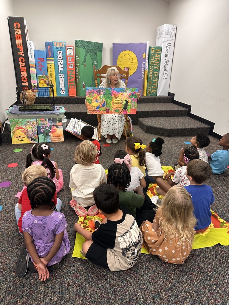 a class listening to a story from a lady and a chicken