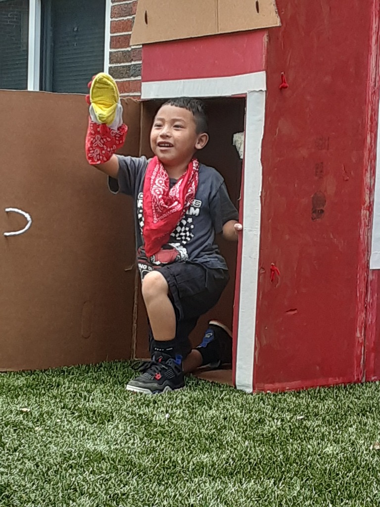 Child playing in a pretend barn with a rooster puppet