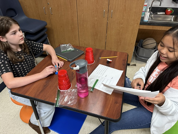 two girls sitting at a table working on a writing project