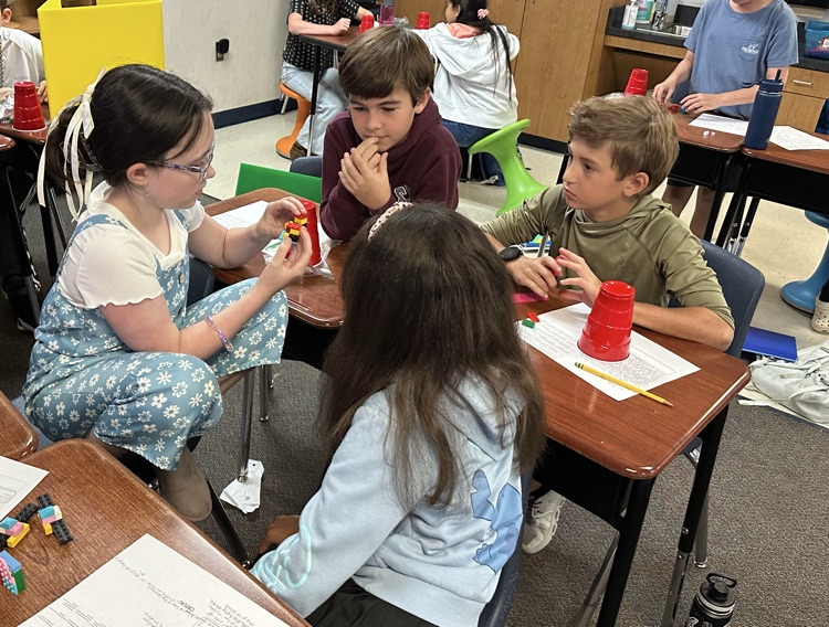 four students sitting around desks working on a writing project