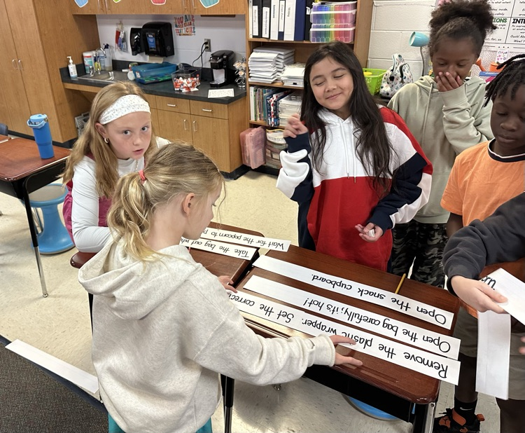 a group of students sit around a group of desks organizing facts in order