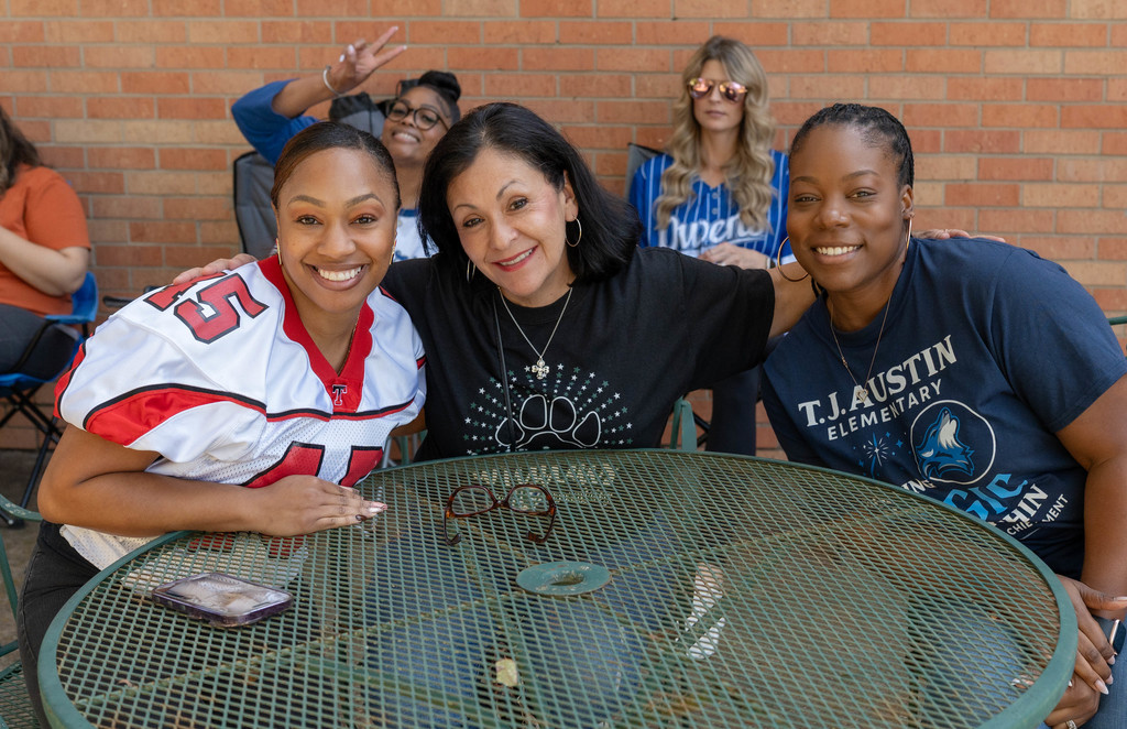 Tyler ISD Principals smile around a table.