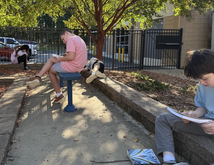 a group of kids reading on benches in a courtyard