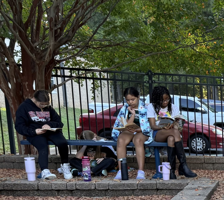a group of kids sitting on a bench reading