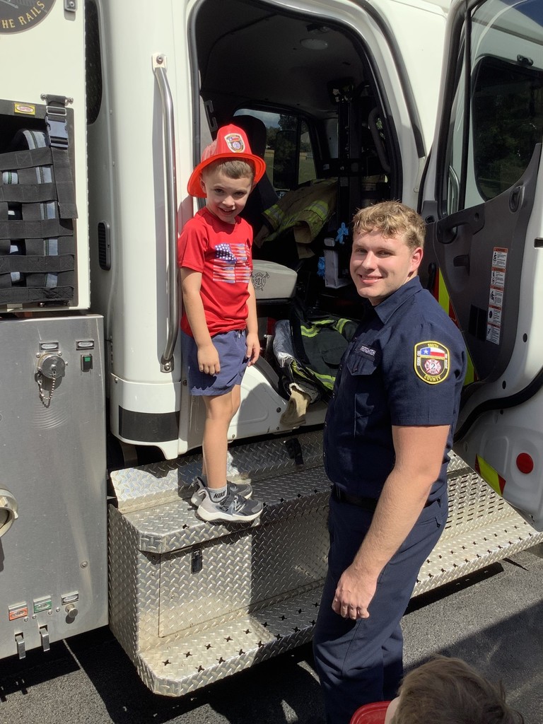 Student posing with fireman by firetruck.