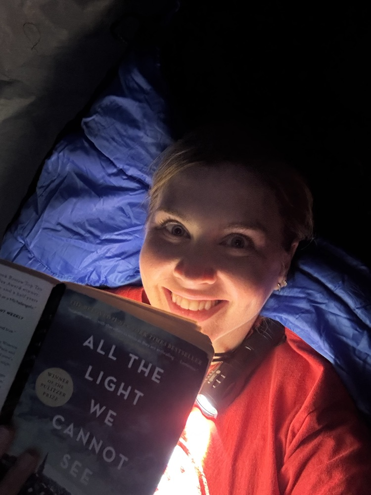 Mrs. OβNeal reading with a flashlight in her tent