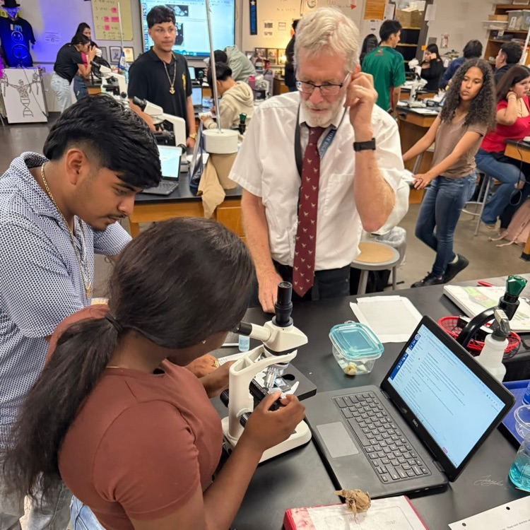 students and teachers at microscope 