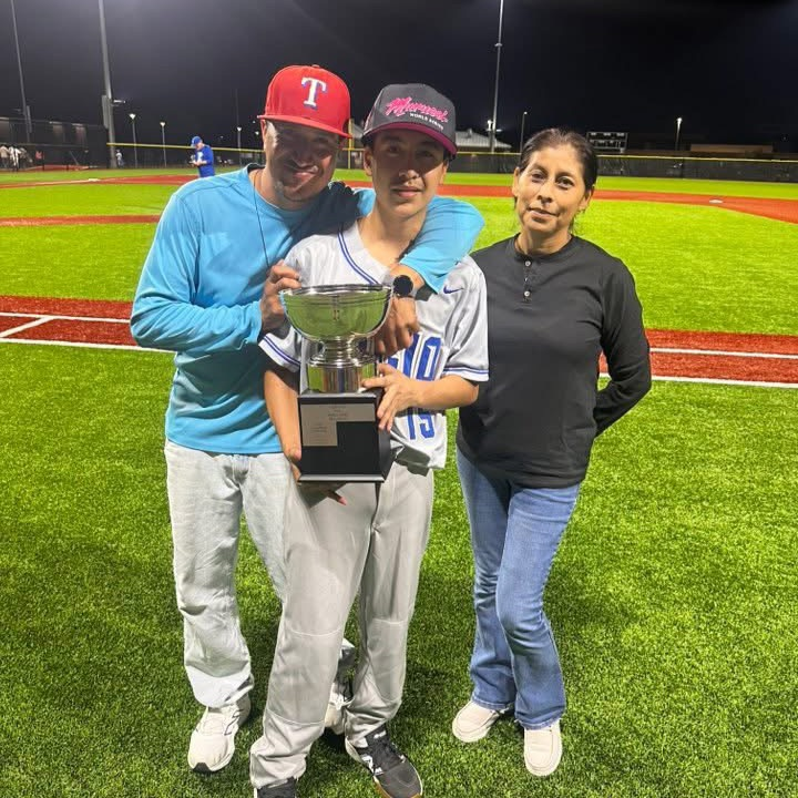boy holding trophy with parents 