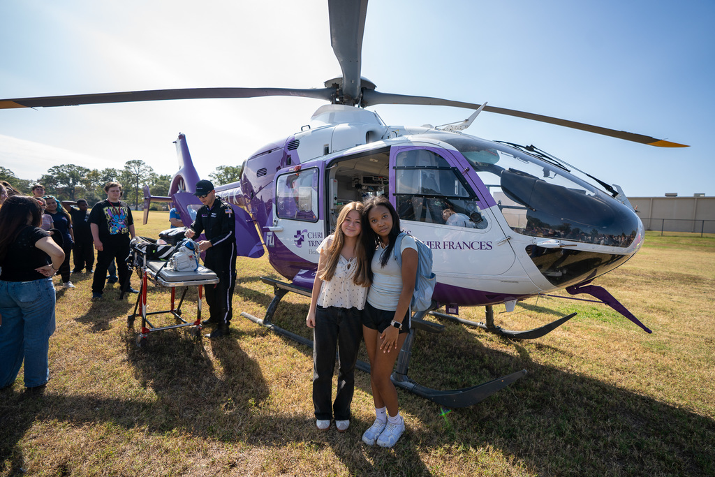 Two Legacy students smile in front of CHRISTUS Flight for Life helicopter.