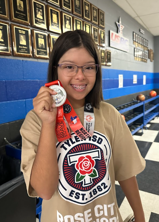 Rose City Warrior student smiling while holding up her medal.
