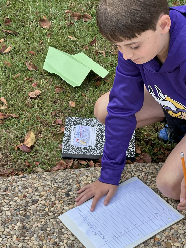 A boy writing sentences outside