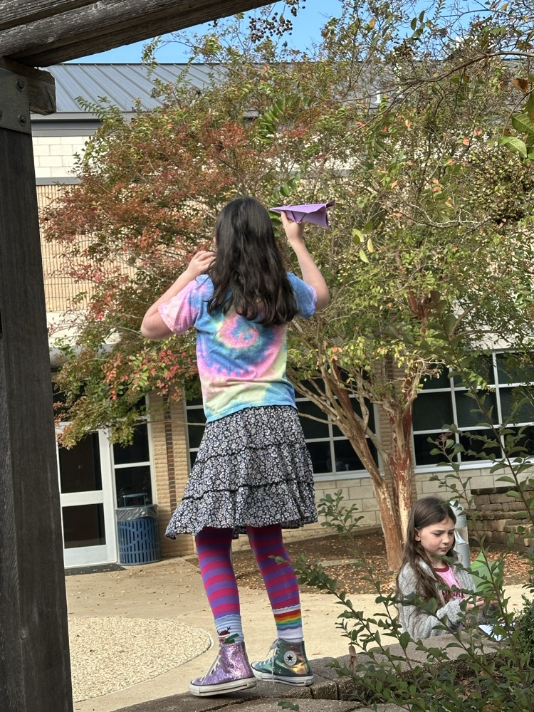 A girl flying a paper airplane 