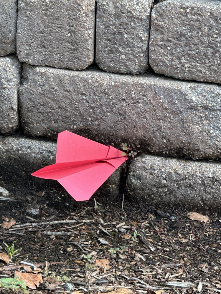 a paper airplane stuck in a brick wall