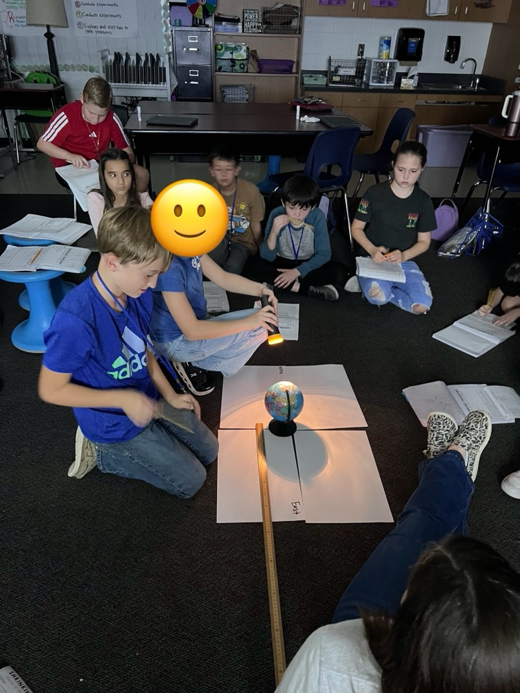 students sitting on the floor of the class watching an experiment about the solar system and light
