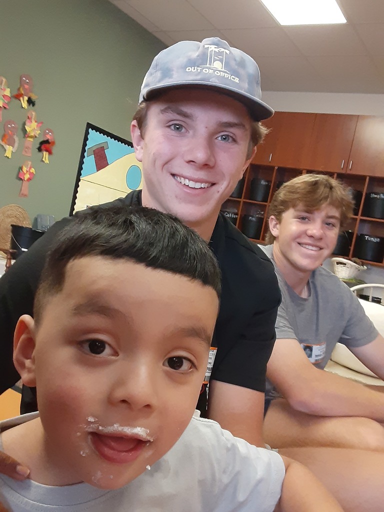 High school students and preschool student eating together