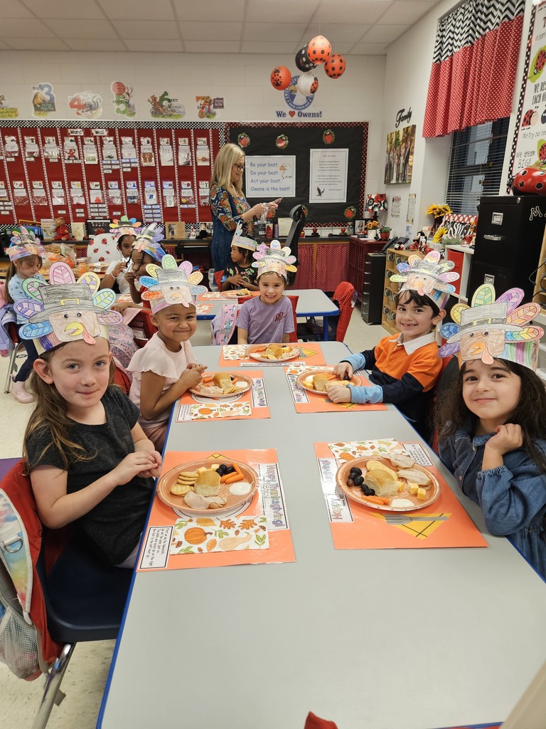 Kindergarten students eating a Thanksgiving snack with cute placemats and turkey hats. 