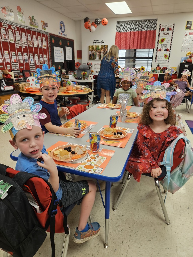 Kindergarten students eating a Thanksgiving snack with cute placemats and turkey hats. 