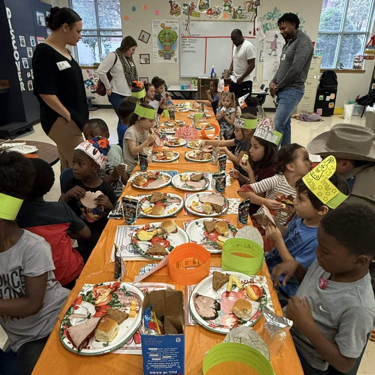kindergarten students partaking in a Thanksgiving feast at a long table