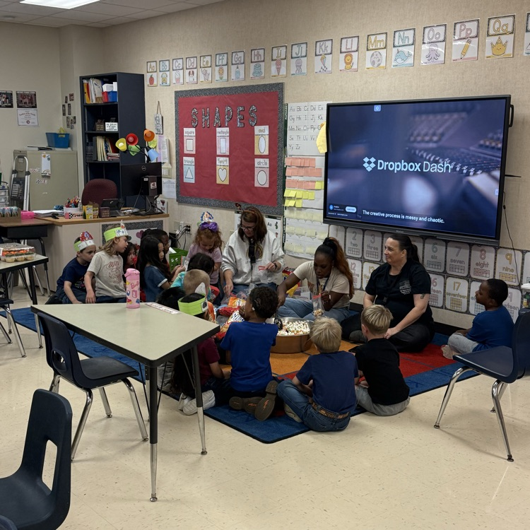 students sitting with teacher in the carpet creating a trail mix